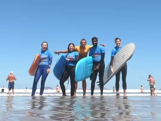 Surf coach Conrad with four students holding surfboards in the shallow water at Playa de Famara.