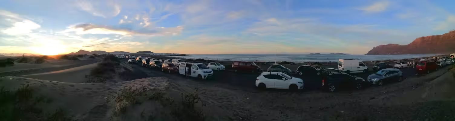 The road next to the beach at sunset. Panoramic view with dunes, beach and and the island of La Graciosa and the horizon.